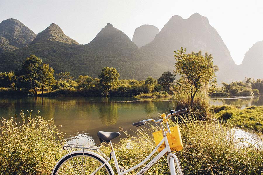 Naturaleza, montañas, agua y una bicicleta con canasta amarilla
